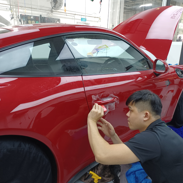 Professional applying paint protection film or ceramic coating on a luxury vehicle.