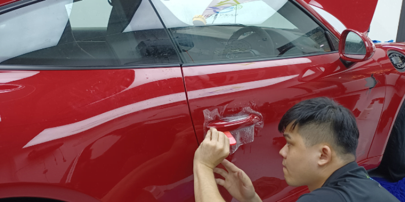Professional applying paint protection film or ceramic coating on a luxury vehicle.